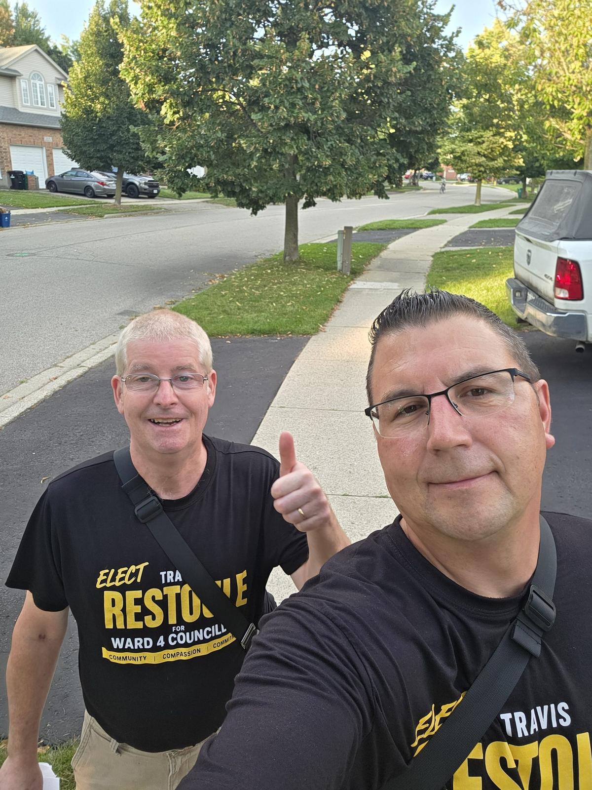 Travis Restoule taking a selfie with a supporter on a residential Ward 4 sidewalk while door knocking